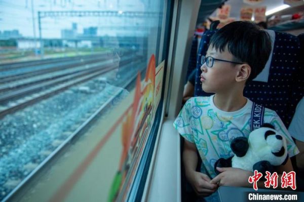 列車啟動后，回香港的郭姓小朋友懷抱著“熊貓”望著窗外?！⒅铱　z